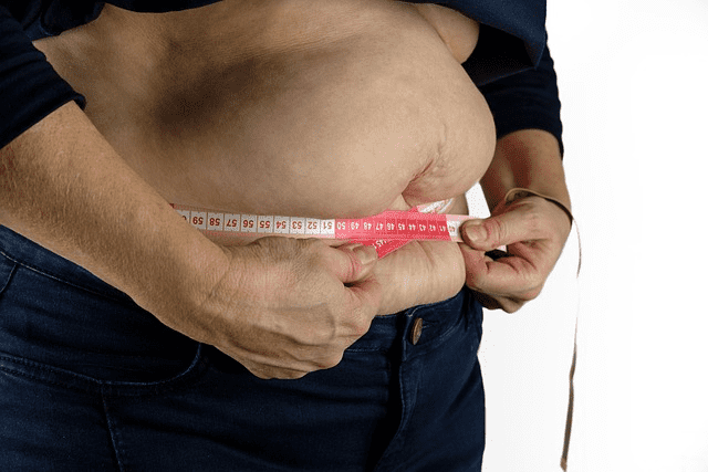 A person measuring their abdomen with a measuring tape.