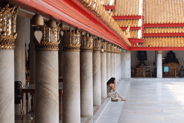 Prospective view of a temple pillars line with a girl sitting in the middle