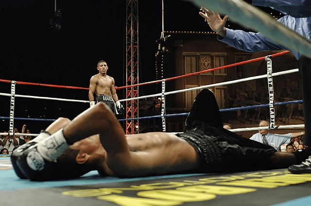 A man lying down on a Boxing ring